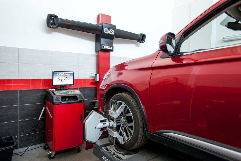 Czerwone auto na stanowisku pomiaru geometrii kół z czujnikami 3D w stacji CarPoint